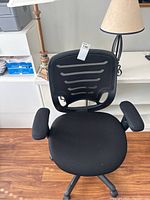 Front view of the black rolling desk chair with mesh back, cushioned seat, and padded armrests
