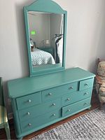 Front and side view of aqua-colored 7-drawer dresser with attached mirror showing overall condition and design.
