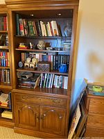 Full view of the wooden shelving unit filled with books and decorative items, showing its size and finish.