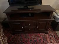 Front view of the dark brown wood TV console with TV on top, showing two drawers and cabinets below and an open shelf for media devices