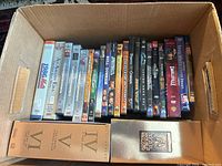Box containing approximately 18 VHS tapes including movies and Star Wars trilogy VHS box set in special casing.