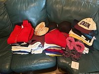 Photo of the full lot including folded tops, hats, slippers on a green couch