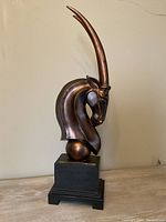 Side view of the bronze sculpture showing curved horns and smooth texture.