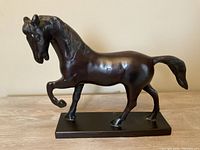 Side view of bronze horse sculpture on rectangular base, showing the form and details of the horse.