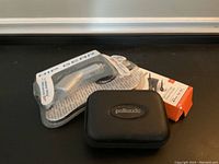 Photo showing new car adapters in sealed original packaging along with a small black carrying case labeled Polk Audio.