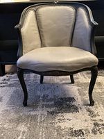 Front view of upholstered chair with dark wooden frame and beige upholstery.