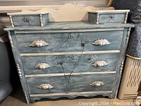 Front view of vintage dresser or vanity showing three drawers with carved pulls and custom floral artwork, along with two small raised drawers on top.