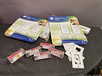 Image showing multiple motion sensing switches from GE, loose white plastic switch faceplates, and small Venkon components packed individually in plastic blister packs on a black surface.