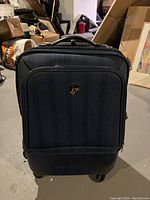 Dark navy blue carry on luggage with front pocket and emblem, on wheels