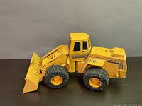 Yellow solid metal CASE front end loader toy side view showing bucket, wheels and cabin