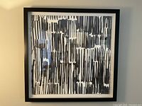 Front view of abstract print with vertical black lines on white background in black frame.