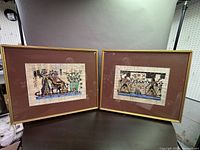 Pair of framed Egyptian art prints with brown matting and gold-tone frames, shown against neutral background.