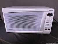 Panasonic white microwave oven with closed door showing control panel and front door design.