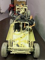 Desert camouflage jeep with two seated military action figures and mounted machine gun viewed from front angle.