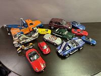 Various die cast car and motorcycle models arranged on black surface