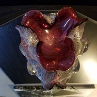 Top view of the red and clear Murano glass dish on a reflective surface.