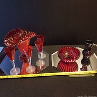 Ruby glass set with large hobnail vases, ribbed bowl, small decanter with stopper, and three champagne flutes displayed on mirrored surface