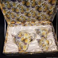 Tea serving set including teapot, creamer, and sugar bowl in floral pattern inside satin-lined box