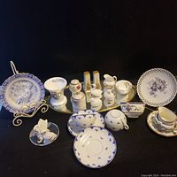 Wide view of entire lot showing the various china items including plates, cups, pitchers, and salt and pepper shakers