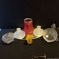 Overview of the lot showing multiple frosted glass floral pieces, red frosted vase, yellow figurine, and a mirrored surface underneath