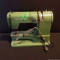 Full side view of the vintage green Elna Supermatic sewing machine showing power cord and foot pedal attached.