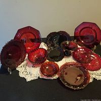 Full arrangement of red glass dishes showing various plates and bowls with intricate patterns.