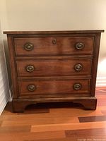 Front view of three-drawer nightstand showing brass ring pulls