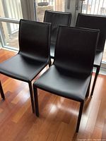 Four black leather chairs in front of balcony doors