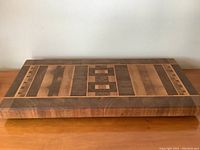 Front view showing full rectangular inlay wood cheese and charcuterie board with geometric patterns.