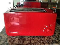 Front view of red KitchenAid toaster on granite counter showing overall condition and design.