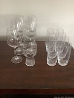 Photo of all 12 glassware pieces arranged on a wooden surface, showing 6 tall wine glasses, 2 short stemmed wine glasses, and 4 highball glasses.
