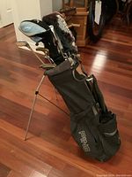 Full view of Ping stand bag holding assorted clubs on hardwood floor