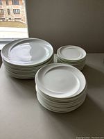 Three stacks of plates on table by window, showing overall count of different sizes