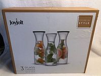 Box front showing brand JoyJolt, image of three glass carafes with fruit and herbs inside, stating 3 glass carafes 36 fl oz each.