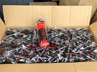 Large cardboard box filled with 50 individually wrapped red water sport bottles with black lids.