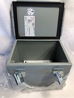 Open electrical box showing interior, documentation inside, and dual latch locks on front.