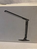 Photo of the front side of the lamp box showing image of the black LED desk lamp with adjustable arm and base.