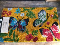 Photo showing the full coir mat with multi-colored butterfly and floral design on a yellow background