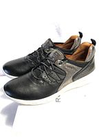 Side angled view of black Rockport women's sneakers showing perforated leather and metallic details