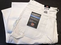 Photo of folded white painter's utility pants with Dickies tag showing size 36x32 and features.