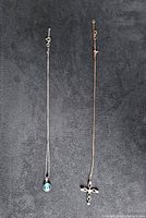 Two sterling silver necklaces laid flat showing pendants and clasps against dark background.