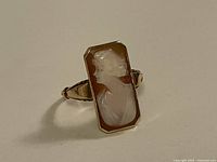 Front view of rectangular cameo ring showing carved woman’s profile set in gold bezel.