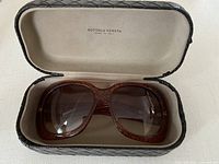 Front view of tortoise acetate sunglasses in case under natural light