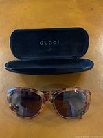 Open black velvet Gucci case with tortoiseshell sunglasses placed on table
