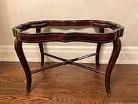 Front view of the vintage coffee table frame showing the scrolled leather wrapped top edge and four cabriole legs with cross stretcher.
