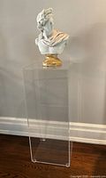 Front view of clear plexiglass pedestal displaying a bust statue on top, showing the full height and transparency of the stand.