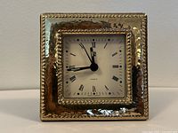 Front view of square clock with hammered sterling silver frame and white Roman numeral dial
