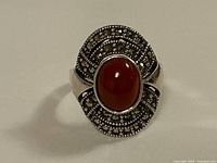 Front view of the sterling silver Art Deco ring showing the oval cabochon carnelian stone centrally set with marcasite stones surrounding it.