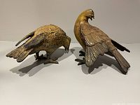 Pair of two different vintage cast iron bird figurines showing front and side views with patina finish