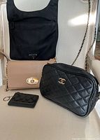 All four items displayed together (Coach tan leather crossbody bag, Chanel black quilted bag, Prada black nylon bag, Coach cardholder)
